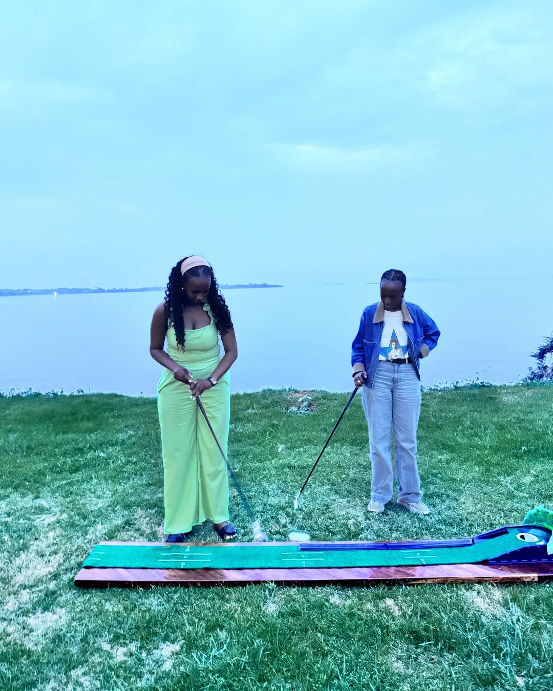 Two girls playing mini golf by the lake
